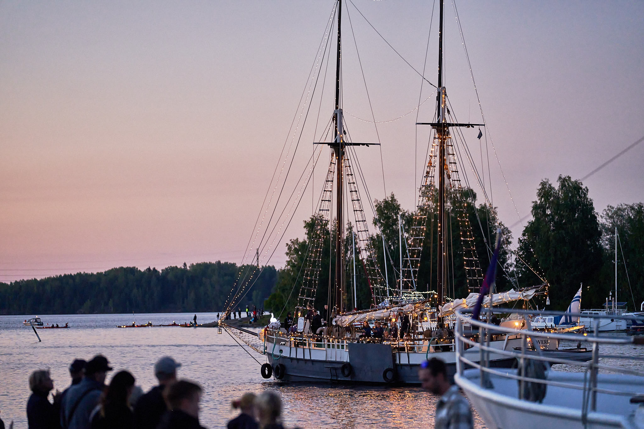 Illalla valoilla somistettu laiva kulkee rannan ohi, jossa ihmiset katselevat sitä Sataman valot -tapahtumassa.